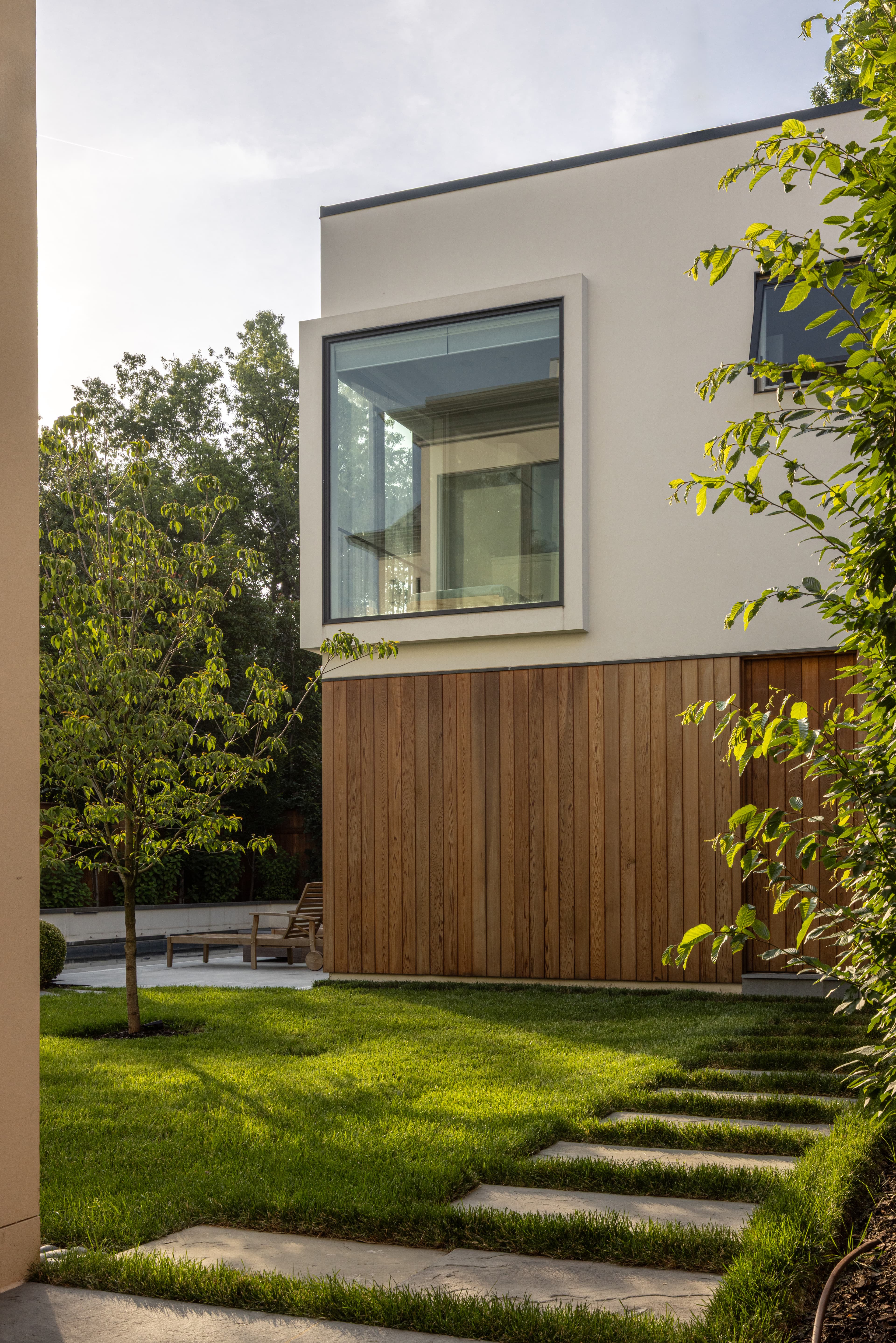 Modern rear elevation with timber cladding and a projecting corner window over the lawn