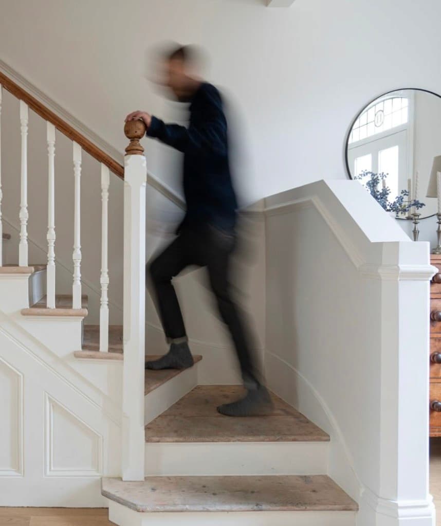 Staircase with a painted balustrade and stripped timber treads, with a round mirror on the landing