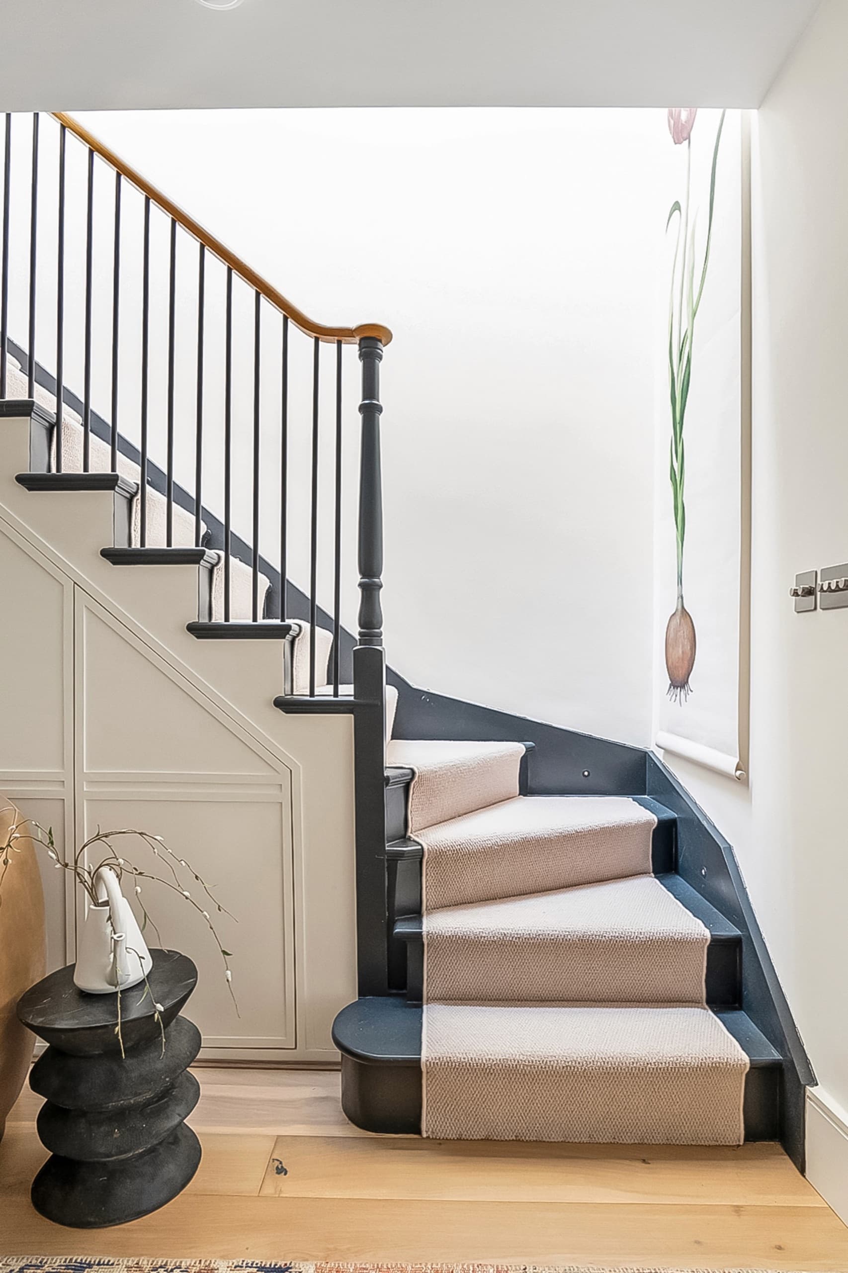 Staircase with a dark painted balustrade, oak handrail and a striped stair runner