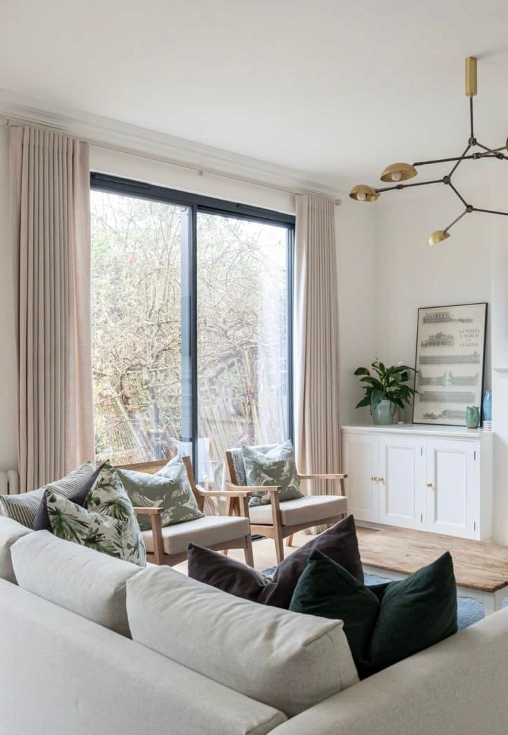 Open-plan living room with full-height sliding doors to the garden and a black branched chandelier