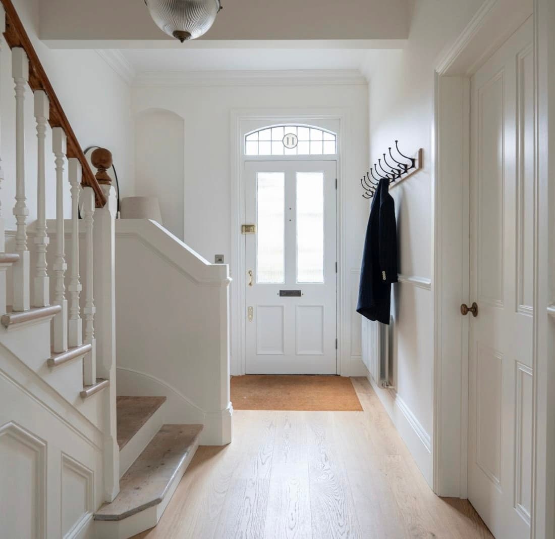 Entrance hall with a white balustraded staircase, panelled front door and pale oak flooring