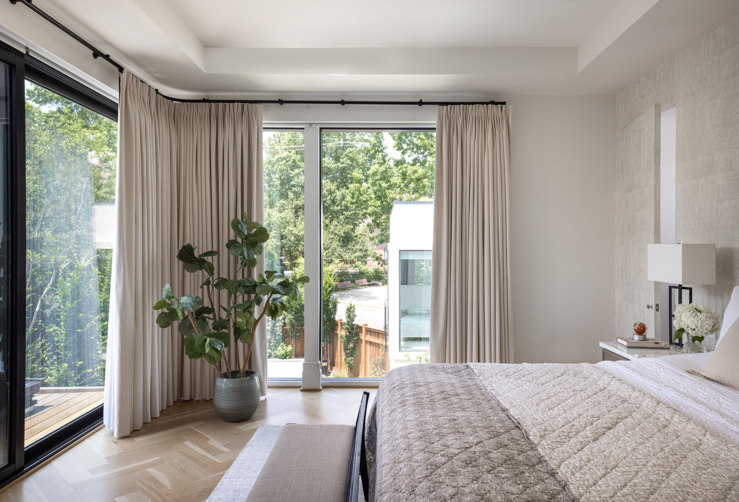 Bedroom with herringbone parquet, floor-length curtains and doors onto a balcony