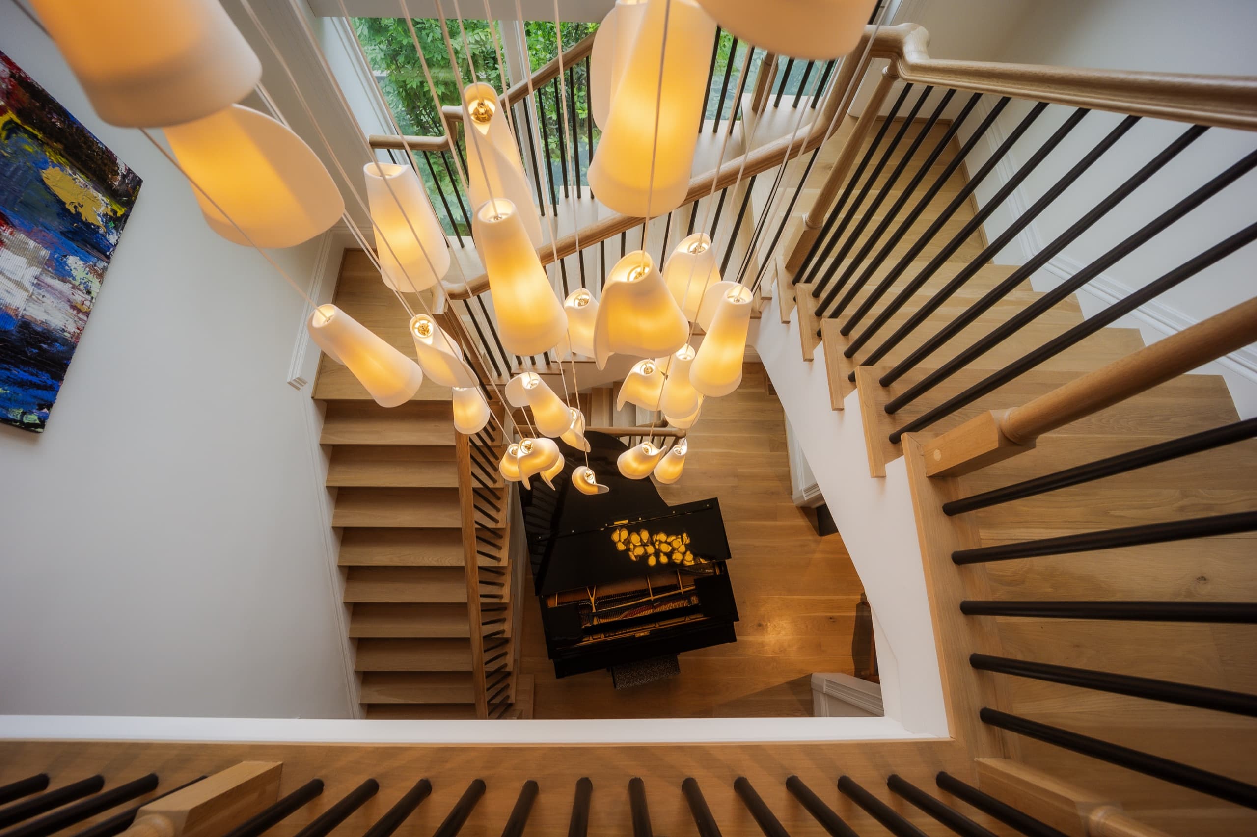 Stairwell seen from above, with a cascading cluster pendant falling through oak treads