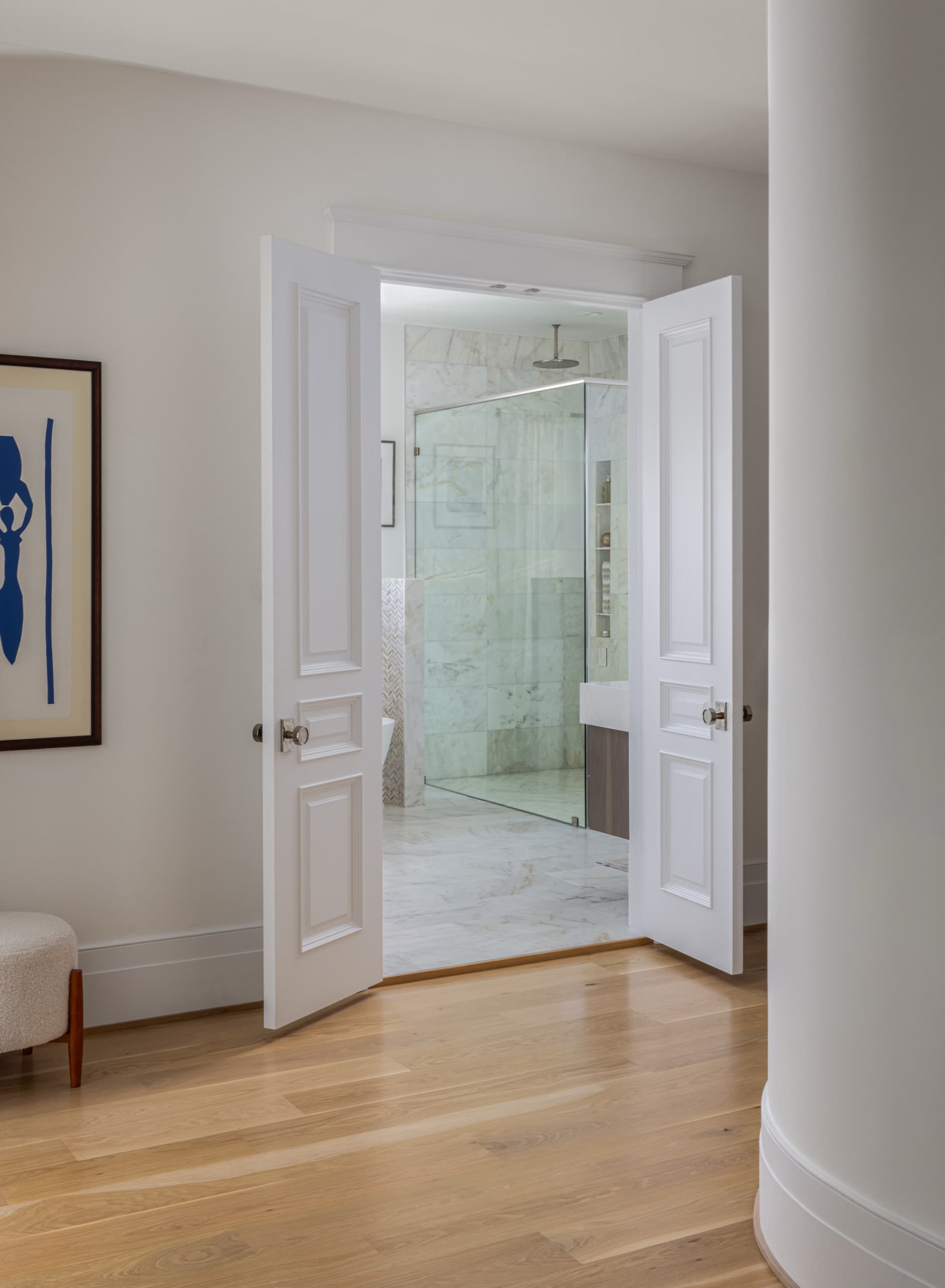 Panelled double doors opening onto a marble-lined shower room